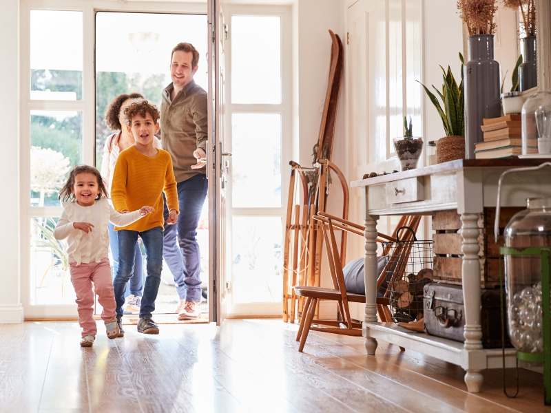 Habitudes d'une famille souriante et heureuse rentrant chez elle après une journée de travail et d'école, représentant l'harmonie et la convivialité familiale.