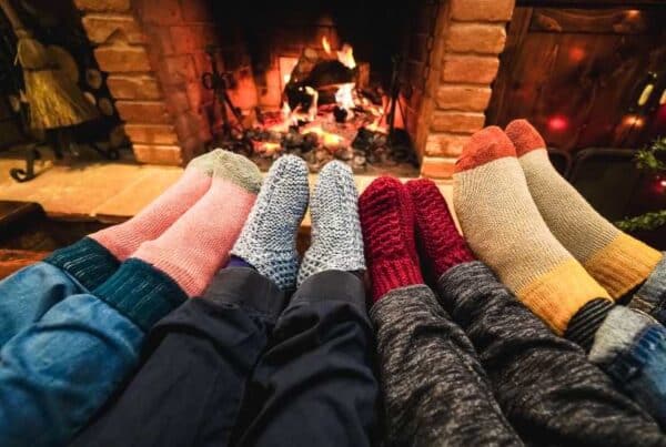 Gérer les conflits avec quatre paires de pieds en chaussettes d'hiver reposant près du feu de cheminée, symbolisant la convivialité et la sérénité familiale