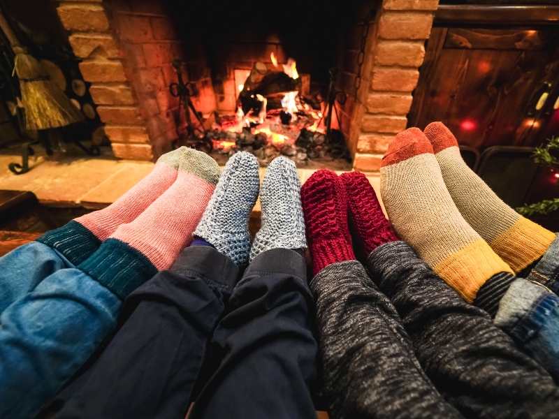 Gérer les conflits avec quatre paires de pieds en chaussettes d'hiver reposant près du feu de cheminée, symbolisant la convivialité et la sérénité familiale